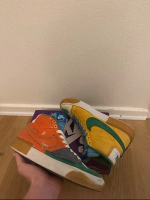 Nike SB Blazer Mid multi-color  - Nike SB Blazer Mid Edge i multicolor. Skejtade ca 3 gånger, så lite gummi/läder saknas vid tån på ena skon - annars fint skick. Box finns kvar.  Fråga gärna om fler bilder!