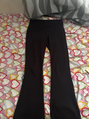 Svarta bootcut byxor med stretch - Säljer ett par svarta bootcut byxor med stretchig passform och hög midja. Byxorna har utsvängda ben och är tillverkade i ett mjukt, följsamt material som ger en snygg siluett. Perfekta för dig som gillar en trendig och bekväm look.