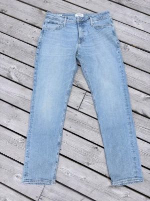 Ljusblå raka jeans från Jack & Jones - Säljer ett par ljusblå raka jeans från Jack & Jones. Klassisk femficksmodell med normal passform och gylf med dragkedja. Perfekta till en avslappnad stil och funkar året runt.