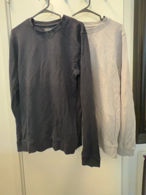 Två basic crewneck tröjor från dressman - Säljer två stilrena crewneck tröjor i bomull, en i mörkgrått och en i ljusgrått. Båda har rund halsringning och långa ärmar, perfekta att matcha med jeans eller joggers. Klassisk och enkel design utan tryck eller mönster.