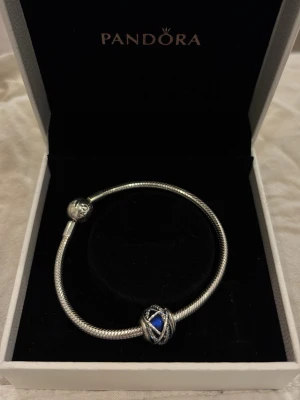 Pandora silverarmband - Säljer ett silverarmband och en berlock från Pandora, som är helt oanvänt och i perfekt skick!✨ På bilden kan man se armbandet samt en berlock som inte säljs längre. Om man vill köpa dem separat, är det bara att kontakt mig☺️ Armbandet försig ligger på 649kr och berlocken ligger på 549kr. Priset tillsammans finns på inlägget💛 Pris kan diskuteras☺️ Lådan på bilden medföljer vid köp av armbandet.