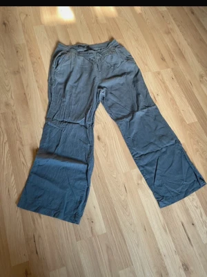 Grå linnebyxor med dragsko - Snygga grå linnebyxor från 157 med avslappnad passform och breda ben. Byxorna har resårmidja med dragsko och sidofickor. Perfekta för en chill och bekväm stil. Materialet är lätt och luftigt linne.