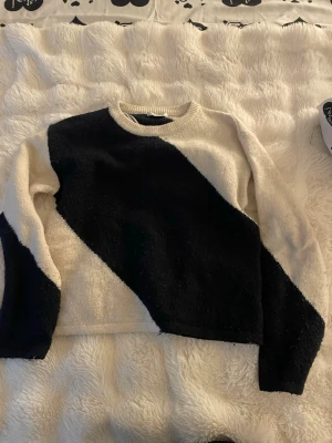 Svartvit stickad tröja med diagonal design - Säljer en stickad tröja i marinblå och vitt med en cool diagonal färgblock-design. Tröjan har rund halsringning och långa ärmar. Materialet känns mjukt och mysigt, perfekt för kyligare dagar. Passar dig som gillar en enkel men ändå unik look.