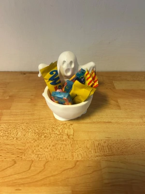 Vit spökskål för godis - En liten vit skål i keramik med ett gulligt spöke som håller om skålen. Perfekt att fylla med godis till halloween eller som dekoration. Skålen har en lekfull design och passar bra som rolig detalj på bordet.