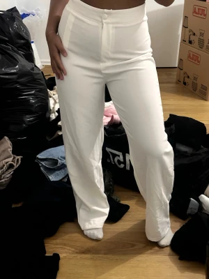 Vita raka kostymbyxor Shein  - Säljer ett par vita kostymbyxor med hög midja och raka ben. Byxorna har en klassisk look med knapp och dragkedja framtill. Materialet ser ut att vara slätt och lite stretchigt, perfekt för en clean och stilren outfit. Storlek xs 