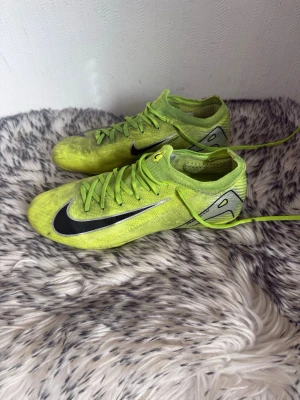 Nike gula fotbollsskor med dobbar - Säljer ett par grymma fotbollsskor från Nike i neon-gult med svarta detaljer och klassisk swoosh på sidan. Skorna har snörning och dobbar för bra grepp på planen. Lätta och smidiga för snabba rörelser. Perfekta för dig som vill sticka ut på fotbollsplanen.