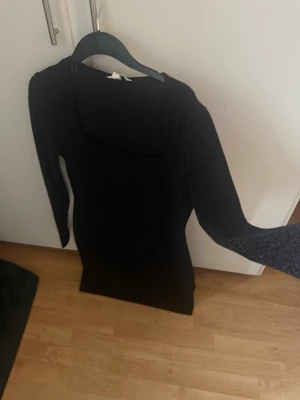 Ny Svart långärmad glittrig  klänning strl L - En svart, figurnära klänning med långa ärmar och Klänningen har en enkel och stilren design som passar perfekt till olika tillfällen.