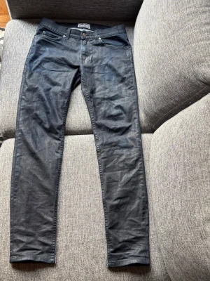 Svarta skinny jeans Acne Studios - Säljer ett par waxed jeans från Acne Studios. Klassisk femficksmodell med smal passform. Jeansen har metallknapp och nitar samt diskreta sömmar. Perfekta till en trendig och avslappnad stil.