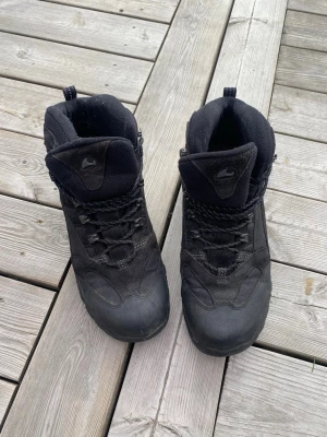 Svarta kängor från Nike - Säljer ett par svarta kängor från Nike med högt skaft och snörning. Kängorna har en robust sula och är tillverkade i en kombination av mocka och textil. Perfekta för kalla dagar och outdoor-äventyr. Klassisk Nike-logga på plösen.