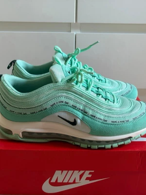 Nike Air Max 97 Mint 'Have A Nike Day' - Nike Air Max 97 sneakers i mintgrönt med texten 'Have A Nike Day' längs sidan. Skorna har vågformade paneler, synlig Air Max-sula och svarta detaljer som swoosh-loggan och dragflik bak. Ovandelen är i textil och syntetmaterial. Perfekt för dig som gillar färg och streetstyle.