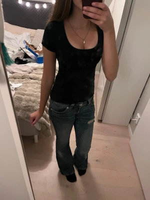 Svart tight topp med rund ringning - Säljer en svart, tight topp med korta ärmar och djup rund ringning. Enkel och stilren design som passar till det mesta. Tillverkad i mjukt material som sitter skönt mot kroppen.