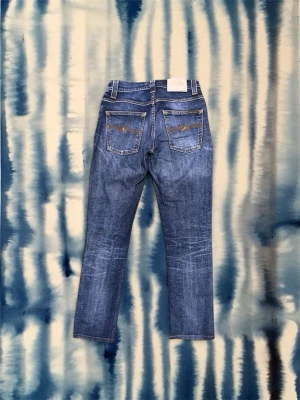 Nudie Jeans  - Snygga blå jeans med raka ben och kontrastsömmar. Jeansen har klassisk femficksdesign och slitningar framtill för en cool look. Materialet är denim i bomull och passformen är normal. Perfekta för dig som gillar en avslappnad men trendig stil. Storlek 28/32. Fin tvätt. Nypris 1600