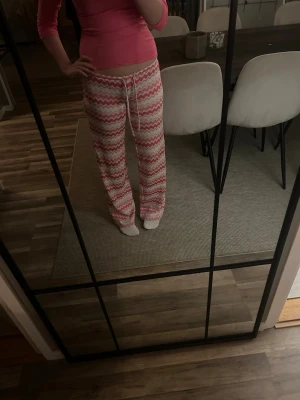 Rosa och vita byxor med mönster - Mysiga byxor i rosa och vitt med zigzag-mönster. Byxorna har dragsko i midjan för skön passform och är tillverkade i ett mjukt, stretchigt material. Säljs inte längre eftersom dom gjorde om designen o matrielet 