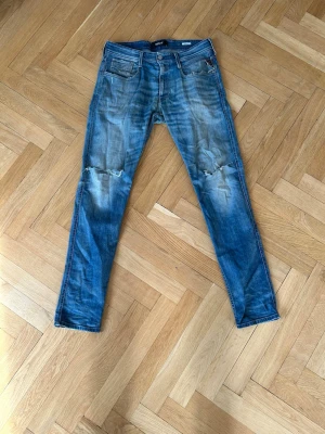 Replay jeans slitningar  - Ett par snygga och unika replay jeans. Slitningar där bak, och två hål vid knäna. Storlek 34/34 men skulle säga att de är lite krympta. 