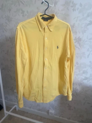 Polo Ralph Lauren Featherweight - Snygg gul skjorta med klassisk krage och knäppning framtill. Skjortan har långa ärmar och en liten broderad logga på bröstet. Perfekt för dig som vill ha en färgklick i garderoben.