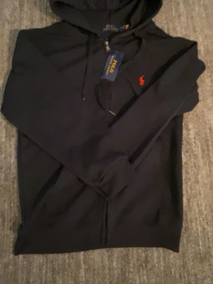  Polo Ralph Lauren zip hoodie - Snygg mörkblå hoodie från Polo Ralph Lauren med dragkedja och huva. Tröjan är helt ny och har en otrolig kvalité. Säljer för 439kr men prismer kan diskuteras vid snabbaffär