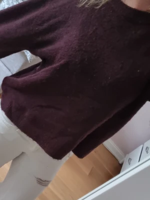 Vinröd stickad tröja - Mysig vinröd stickad tröja med rund halsringning och långa ärmar. Tröjan har en enkel, rak passform och är tillverkad i ett mjukt material som passar perfekt för kyligare dagar.