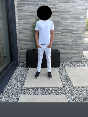 Vita Replay Jeans  - Replay Anbass Hyperflex jeans i vitt, storlek W30/L32. Snygg slim fit-modell med stretch. Personen på bilderna är 189 cm lång och väger ca 76 kg, och byxorna sitter något kort och tajt på honom, så de passar troligtvis bättre på någon som är lite mindre. Jeans i fint begagnat skick med normala spår av användning. Replay-märket baktill vid bakfickan har gått sönder och är delvis lossnat, vilket syns på bilderna. I övrigt fint skick. Nypris ca 1 700–2 000 kr.
