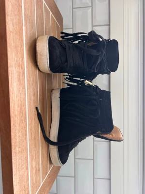 Niche Svarta kilklack skor med fransar - Säljer ett par svarta kilcklackar sneakers aktiga skor med fransdetaljer på . Materialet är mocka.    Perfekta för dig som vill sticka ut med din stil.