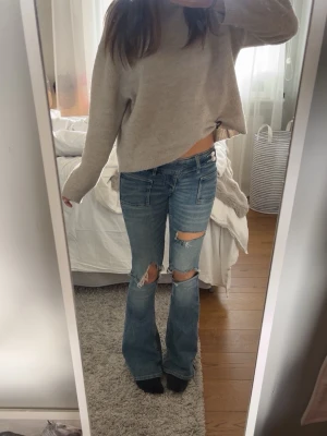 Blå slitna bootcut jeans - Säljer ett par blå bootcut jeans med slitningar och hål på knäna. Väldigt sköna och mjuka men kommer tyvärr inte till användning längre.