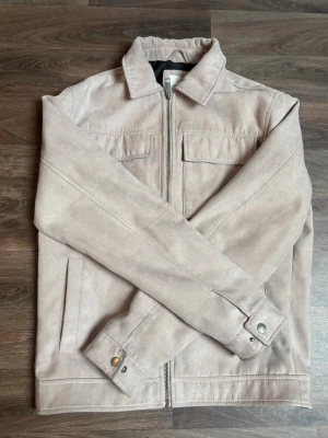 Overshirt från Jack and Jones  - Snygg beige overshirt med dragkedja framtill, två bröstfickor med lock och sidofickor. Klassisk krage och knappdetaljer vid ärmslut. Perfekt för lager på lager och enkel att styla. Längesen jag köpte men tror nypris runt 700