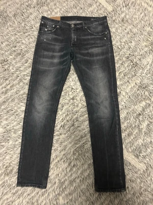 Svarta jeans i regular fit - Snygga svarta regular fit jeans med slitningar och tvättade detaljer från Dondup. 
