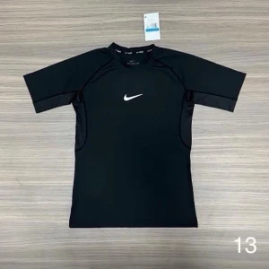 Svart träningströja från Nike - Snygg svart träningströja från Nike med korta ärmar och vit logga på bröstet. Tillverkad i ett stretchigt funktionsmaterial som andas, perfekt för gymmet eller löpning. Sportig passform och stilren design.