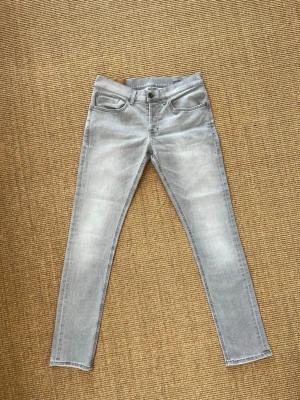 Dondup Ljusgrå  - Snygga ljusgrå jeans i slim fit-modell med klassisk femficksdesign och knappgylf. Jeansen har en tvättad look och raka ben. Perfekta för en avslappnad och trendig stil.