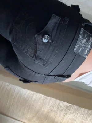 Svarta bootcut jeans från True Religion - Säljer ett par svarta bootcut jeans från True Religion. De har blivit använda två gånger så de är i nyskick. Storlek W24!