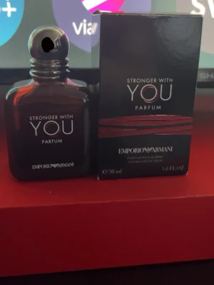 Stronger With You Parfum - Emporio Armani Stronger With You Parfum i en elegant mörkbrun glasflaska med rundad form och silverdetaljer. Flaskan rymmer 50 ml och typ 30 ml kvar och kommer med originalkartong i svart med röda och silverfärgade detaljer. En stilren och modern doft för dig som gillar exklusiva parfymer.