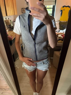 Ralph Lauren väst grå - Ralph Lauren väst med hög krage och fickor. Grå stickad med mörkblå zip.