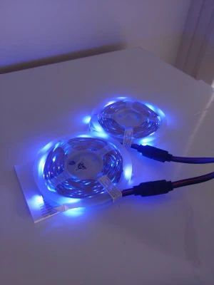 20m RGB LED-list med fjärrstyrning - Två rullar flexibla RGB LED-lister som kan lysa i olika färger, bland annat blått och grönt. Perfekt för att skapa stämningsbelysning i rummet. Lister med genomskinligt plastmaterial och svarta anslutningskablar. Enkel att installera och styra via fjärrkontroll.