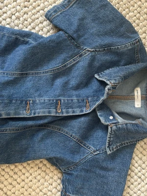 Kortärmad jeansskjorta i denim - Säljer en snygg kortärmad skjorta i blå denim med klassisk krage och knappar framtill. Skjortan har en figurnära passform och är gjord i bomull. Perfekt till jeans för en cool denim-on-denim look.