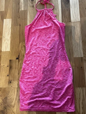 Rosa halterneckklänning - Säljer en snygg rosa halterneckklänning med melerad effekt. Klänningen har smal passform och knyts i nacken. 