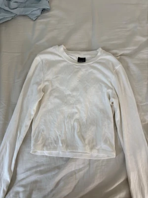 Vit långärmad topp från Gina Tricot helt ny och oanvänd - En enkel och stilren vit långärmad topp från Gina Tricot. Modellen har rund halsringning och är tillverkad i mjuk bomull, perfekt att matcha med jeans eller kjol för en clean look. Nypris 200kr jätteskönt material