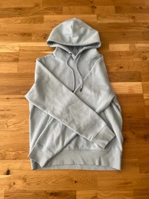 Ljusblå hoodie från Jack&jones - Säljer en stilren ljusblå hoodie med huva och dragsnören. Hoodien har ribbade muddar vid ärmslut och nederkant samt en klassisk passform. Perfekt för dig som gillar en enkel och clean look. Materialet känns mjukt och bekvämt.