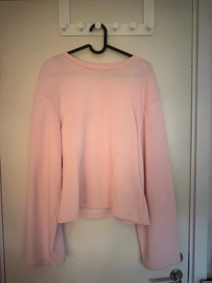 Ljusrosa  sweatshirt  - En enkel och stilren ljusrosa sweatshirt med en liten tajtare vid midjan och långa ärmar. Tröjan har rund halsringning och är gjord i ett mjukt, bekvämt material som passar perfekt för en avslappnad look. Tröjan har handvänds 2 gånger. 