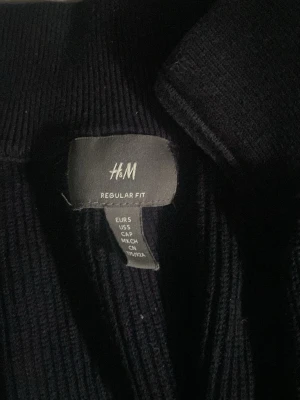 Mörkblå ziptröja från H&M - Mörkblå ribbstickad ziptröja från H&M i regular fit. Tröjan har hög krage, dragkedja framtill och långa ärmar. Perfekt för lager på lager och enkel att matcha med olika outfits.