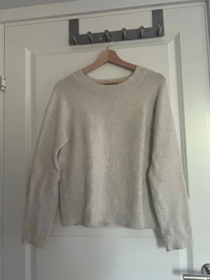 Beige stickad tröja med rund hals - Mysig beige stickad tröja med rund halsringning och långa ärmar. Tröjan har ribbstickade muddar vid ärmslut och nederkant. Perfekt för lager på lager och enkel att matcha till olika outfits. Hela varan är nopprig.