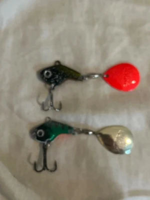 Två fiskedrag i olika färger - Säljer två fiskedrag med fiskhuvudform och trekrok. Ena draget har svart/grönt huvud och röd sked, det andra har grönt huvud och silverfärgad sked. Perfekta för fiskeentusiasten som vill ha variation i beteslådan.