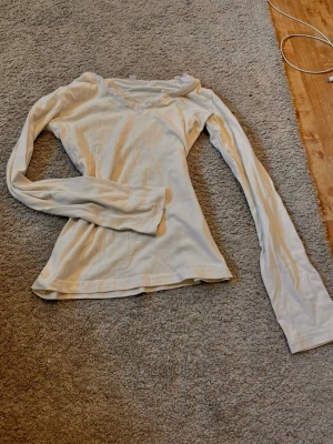 Vit långärmad topp med spets vet ej märke - Säljer en enkel och stilren vit långärmad topp med v-ringning och spetsdetalj vid halsen. Toppen har en smal passform och är tillverkad i ett mjukt material som känns skönt mot huden. Perfekt att matcha med jeans eller kjol. Varumärket kan vara hollister  men vet ej