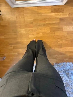 Mörkgrå utsvängda kostymbyxor - Säljer ett par mörkgrå kostymbyxor med utsvängda ben, byxorna har perfekt passform och är i storlek 36. Från BikBok.