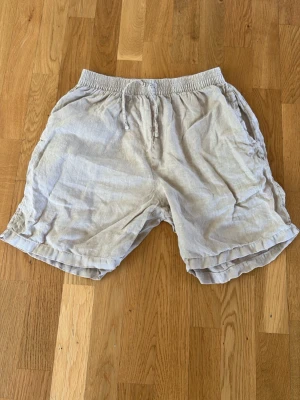 GANT Sandfärgade linneshorts (100%) med snörning - Snygga shorts i 100% linne från GANT med elastisk midja och snörning. Sandfärgade. Shortsen har en loose passform. Bild nr 2 är lånad.  Storlek 158/164 men stora i storleken. Killen på bilden är 165 cm. Mycket fint skick. 