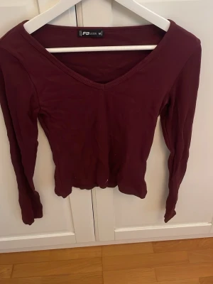 Vinröd långärmad v-ringad topp - Säljer en enkel och snygg vinröd långärmad topp med v-ringning. Perfekt att matcha med jeans eller kjol för en clean look. Materialet känns mjukt och stretchigt, vilket gör den bekväm att bära hela dagen. Så snygg till ett par jeans, älskar😻