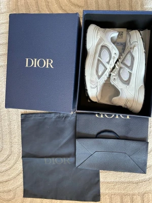Vita b30 - Säljer ett par snygga vita  sneakers med grå detaljer och meshpaneler. Skorna har chunky sula, klassisk snörning. Perfekta för dig som vill ha en exklusiv och trendig look. Levereras med originalkartong och dustbag.