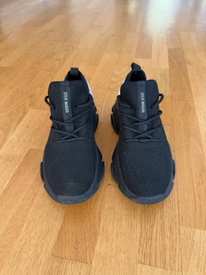 Steve Madden Protege-e svarta sneakers - Svarta chunky sneakers från Steve Madden med grov sula och stickad ovandel. Skorna har vita logotyper på plösen och hälen, samt svarta skosnören. Snygg och modern design som passar till streetwear och casual outfits.