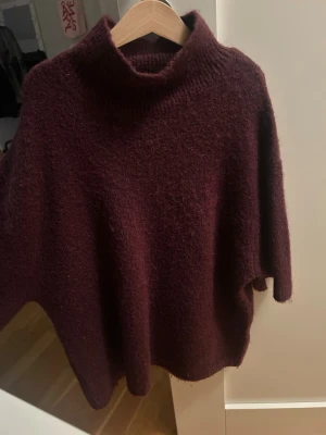 Vinröd stickad polotröja Gina Tricot - Mysig vinröd stickad polotröja från Gina Tricot i ullblandning. Tröjan har en lös passform, bred polokrage och är tillverkad i ett fluffigt material som känns riktigt skönt. Perfekt för kalla dagar och enkel att styla med jeans eller kjol.