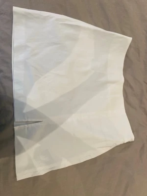 Kort vit kjol  - Simpel vit minikjol med slits som sitter åt låren. Bredaste punkten är 47cm (längst ner) och vid midjan är bredden 36cm (högst upp). Använd 1-2 gånger💞