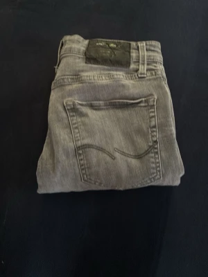 Grå jeans Slim fit - Säljer dessa grå jeans i slim fit från Jack&Jones. Jeansen är i bra skick och säljes billigt. Storlek 29/30. Skriv in vid eventuella frågor om jeansen!