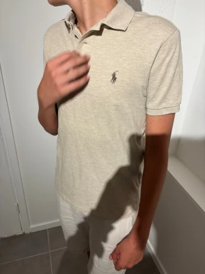 Polo Ralplauren piqe - Snygg beige pikétröja med klassisk krage och korta ärmar. Tröjan har en liten broderad logga på bröstet och är tillverkad i ett mjukt bomullsmaterial. Perfekt till jeans eller shorts för en clean look.